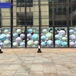 Multiple Inflatable Beach Balls Behind Six Glass Walls