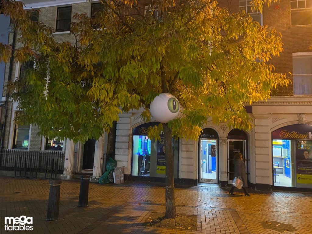 Inflatable eye attached to a tree in the dark