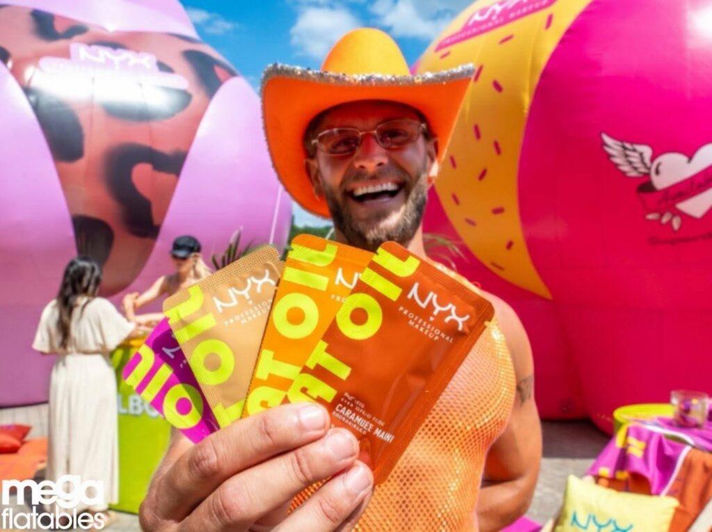 man in cowboy hat holding nyx products infront of inflatables - megaflatables